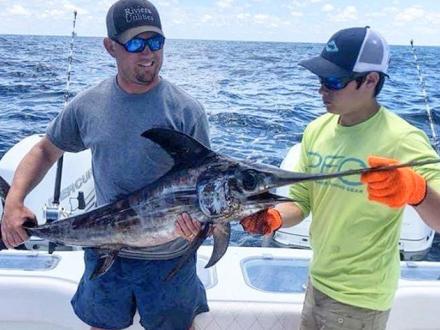 Fishermen hold swordfish on Alabama Gulf Coast