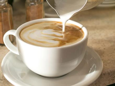 Cup of creamer being poured into a cup of coffee at BuzzCatz in Orange Bach