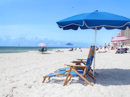each chairs and umbrellas set up on the white sands of Alabama's Gulf Coast, providing a relaxing gulf front experience