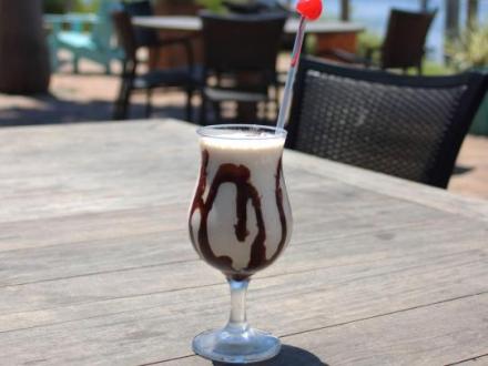 A creamy bushwacker cocktail drizzled with chocolate syrup, served in a glass with a cherry on top at Cobalt restaurant in Orange Beach, Alabama