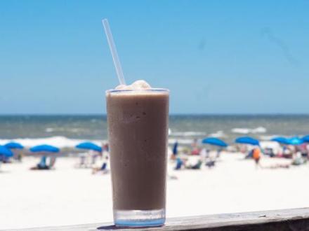 Bushwacker from Pink Pony Pub served in a tall glass with a beach view in Gulf Shores