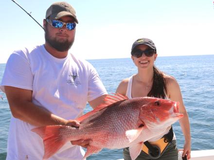 Anglers holding a red snapper caught offshore in Orange Beach