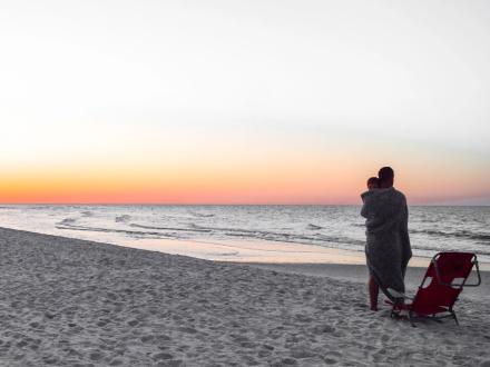 Dad and child watching the sunrise on the beach in Gulf shores