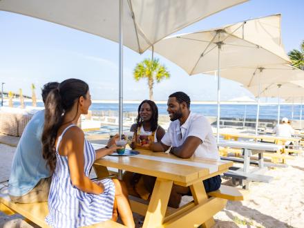 Two couples enjoying drinks and dinner at The Gulf in Orange Beach, AL