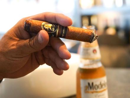 Hand holding a cigar at the bar of Shore Things Cigars in Orange Beach
