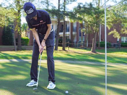 Man putting a golf ball at One Club golf course in Gulf Shores