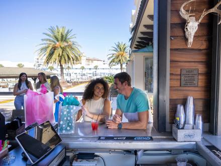 Couple sitting at the bar with shopping bags at the courtyard in SanRoc Cay