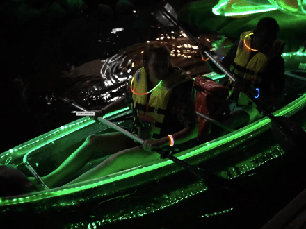 Couple in a neon lighted, clear kayak going on a nighttime tour with Sea View Tours in Orange Beach