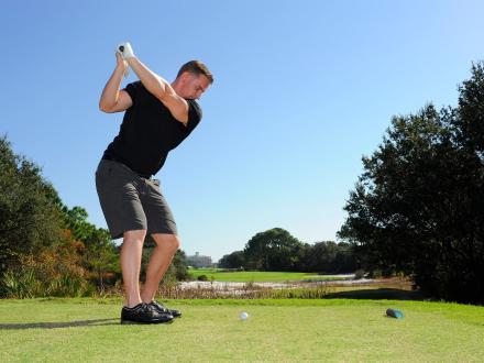 Man swinging golf club at Kiva Dunes golf course in Fort Morgan