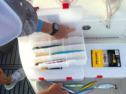 Hand reach into a tackle box on a fishing charter in Orange Beach