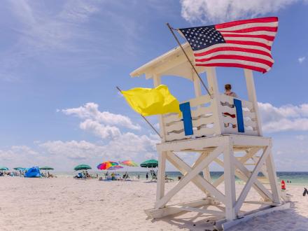 Yellow beach flag and American flag on a lifeguard stand at the beach in Gulf Shores