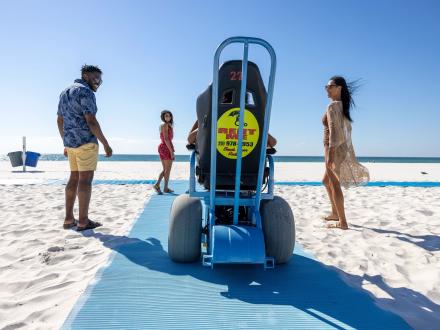 Family with daughter in an electric wheelchair going to the Gulf on a beach mat