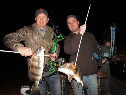 Two men holding up fish caught while bow fishing in Orange Beach