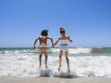 Two young kids jumping over a wave at the beach in Gulf Shores