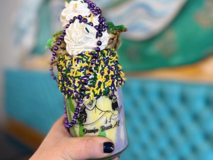 Massive king cake milkshake decorated with beads and sprinkles at Milkshake Momma in Orange Beach