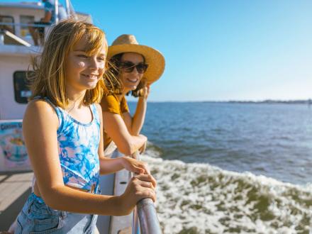 Mom and daughter on a dolphin cruise looking out into the Gulf