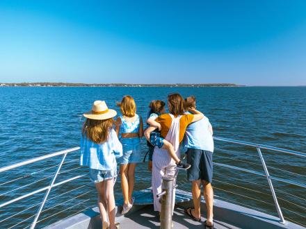 Family standing a bow of a dolphin cruise looking out into the Gulf in Orange Beach