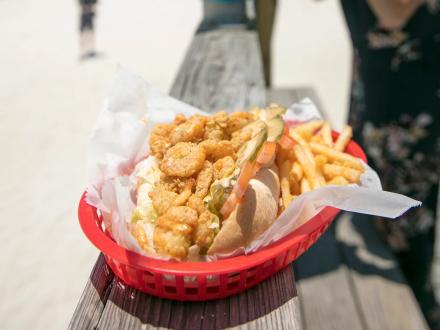 a basket with a shrimp po'boy and fries at Pink Pony Pub beachfront restaurant
