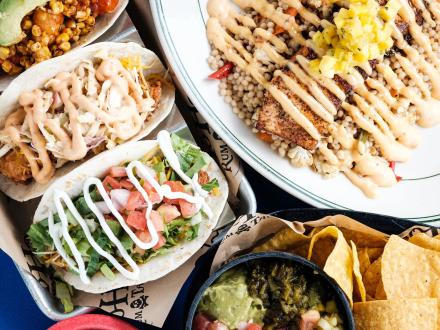 a table full of tacos, fish, and guacamole at Yoho Rum & Tacos Mexican restaurant in Orange Beach