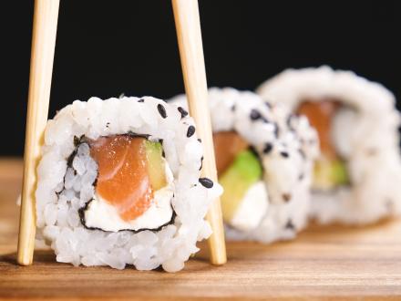 A pair of chopsticks picking up a piece of sushi from a board