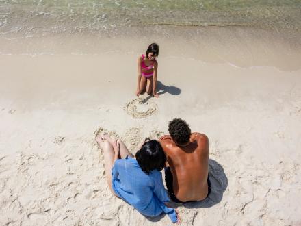 Couple with a daughter sitting on the sand near the shore