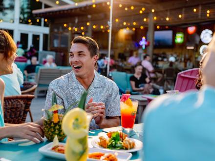 Friends dining around a table of food at GTS on the Bay waterfront restaurant in Orange Beach