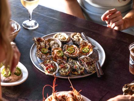 a plate of baked oysters sitting on a table at The Steamer beach restaurant in Gulf Shores
