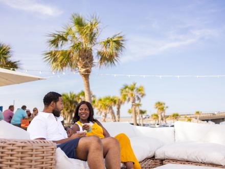 Couple dining on a couch by. the beach at The Gulf restaurant in Orange Beach