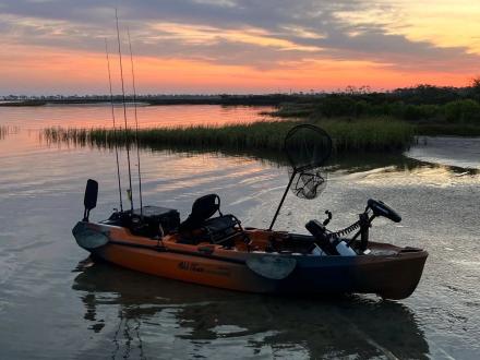 kayak rigged for fishing sitting in the water at sunset