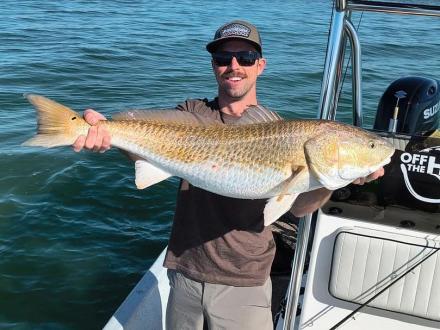 Man holding a redfish caught in the Gulf during a charter fishing trip from Orange Beach