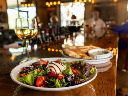 A summer strawberry salad and a glass on wine sitting on the bar at Savanna Restaurant in Gulf Shores