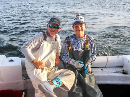 Man and boy sitting on a deep-sea fishing charter boat in Orange Beach