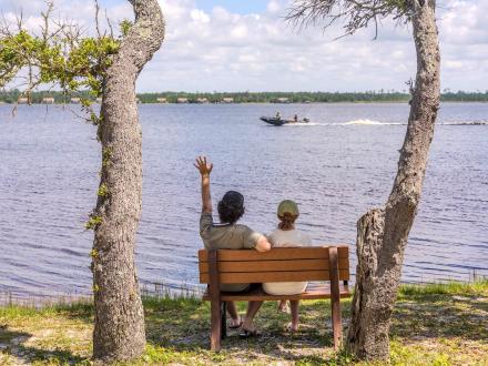 Two people sitting on a beach looking out onto scenic Lake Shelby
