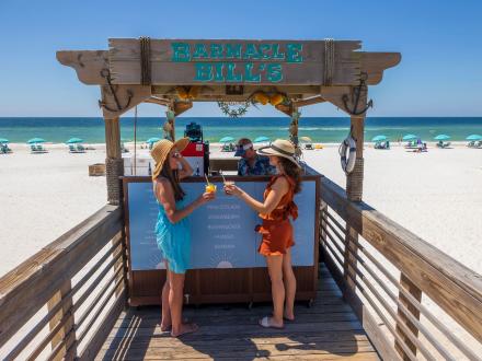 Two women grabbing drinks from the boardwalk bar at The Lodge in Gulf Shores