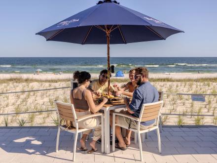 Friends dining on the outdoor patio at Coastal beachfront restaurant in Orange Beach