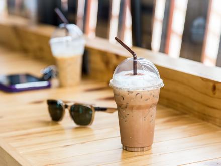 to-go cups of iced coffee sitting on a table next to a pair of sunglasses