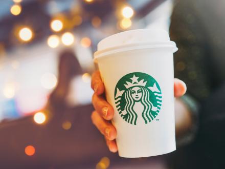 hand holding a to-go cup of coffee from Starbucks