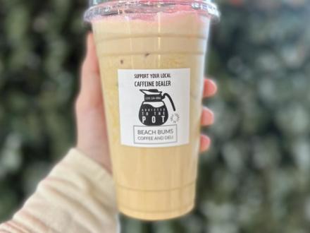 Hand holding a to-go cup of iced coffee from Bay's Deli