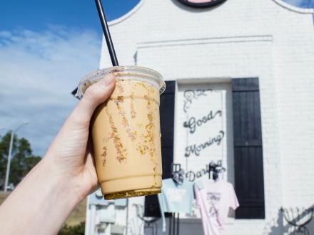 Hand holding up a to-go cup with iced coffee at Beach Girl drive through coffee shop in Gulf Shores