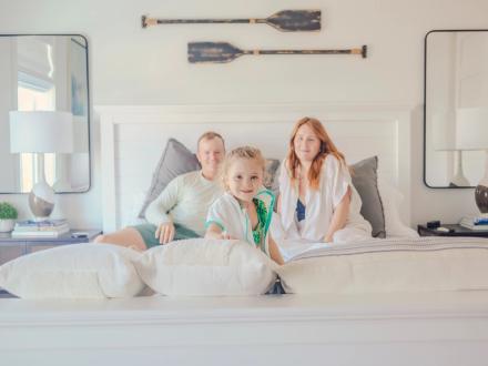 Family sitting on a bed inside a beach house in Orange Beach