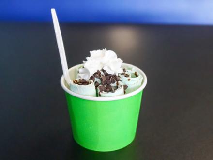 a green cup of mint ice cream with chocolate chi[s and whipped cream at Cowbell Rolle Ice Cream