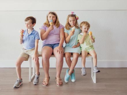 Kids sitting on a bench eating ice cream cones at Del's Ice Cream in Gulf Shores