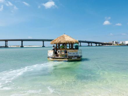 Tiki boat cruise floating in the water near Perdido Pass Bridge in Orange Beach