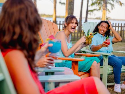 Friends sitting on Adirondack chairs by the bay at GTs waterfront restaurant in Orange Beach