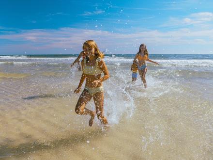 Kids running towards the shore from the water on the beach in Gulf Shores