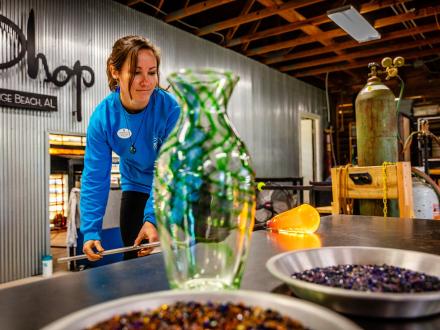 Woman creating a glass blown vase at The Hot Shop in Orange Beach