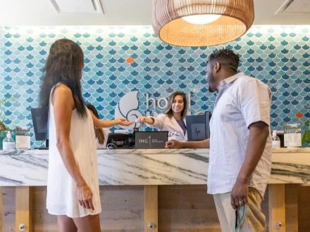 Couple grabbing room keys from the front desk at Hotel Indigo in Orange Beach