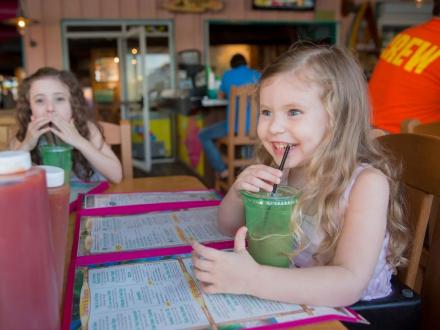 Young girls smiling at a table at LuLu's family-friendly restaurant in Gulf Shores