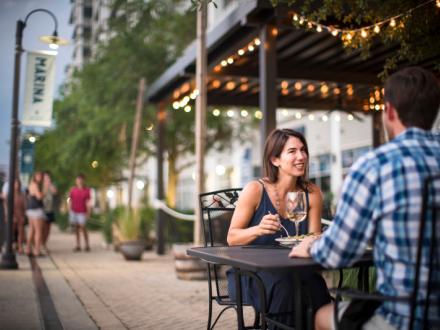 Couple dining outdoors by the water at Ginny Lane restaurant at The Wharf