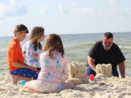 Family building sandcastles during a class with Sand Castle University on the beach in Gulf Shores